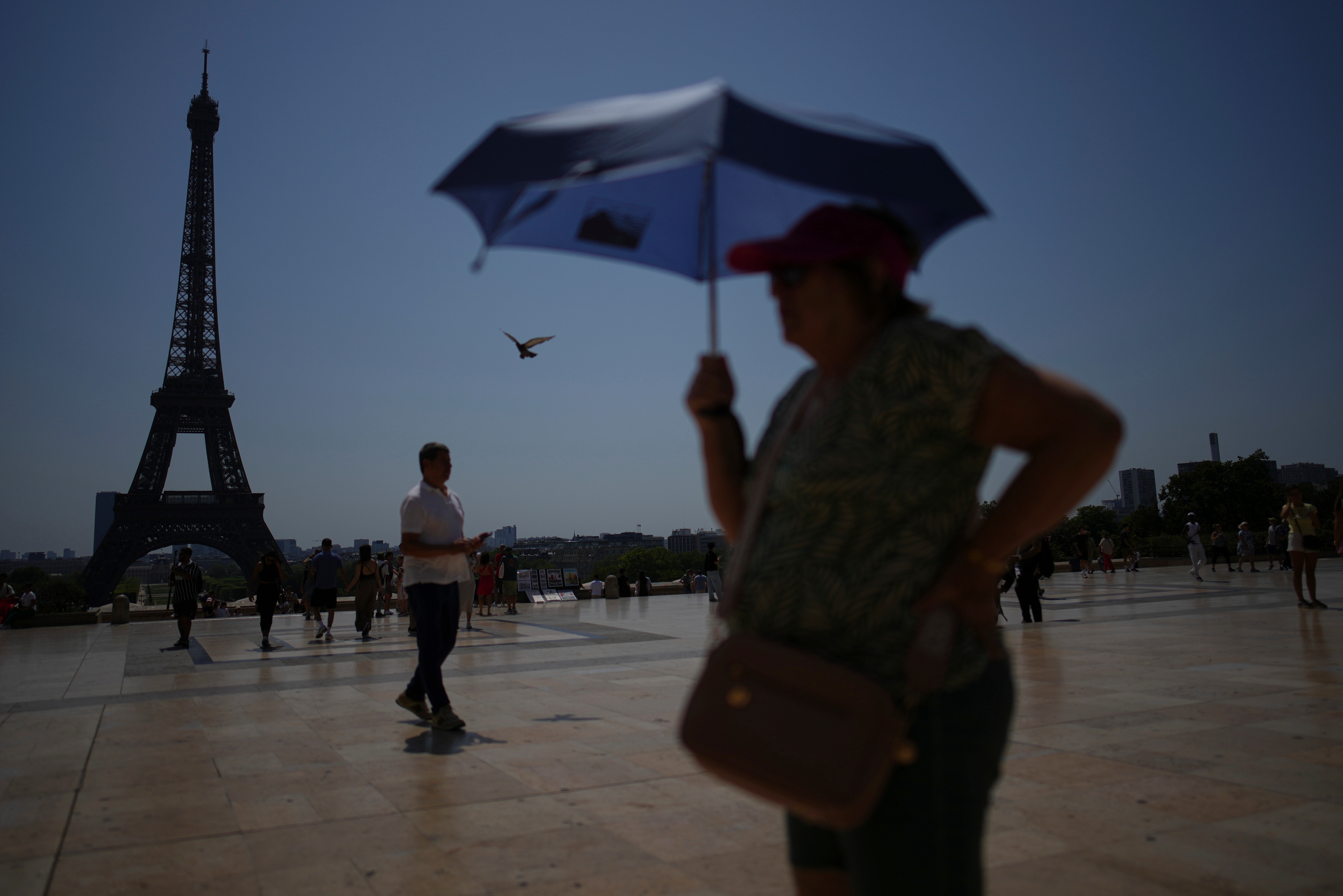 People walk at Trocadero plaza near the Eiffel Tower during a heat wave.