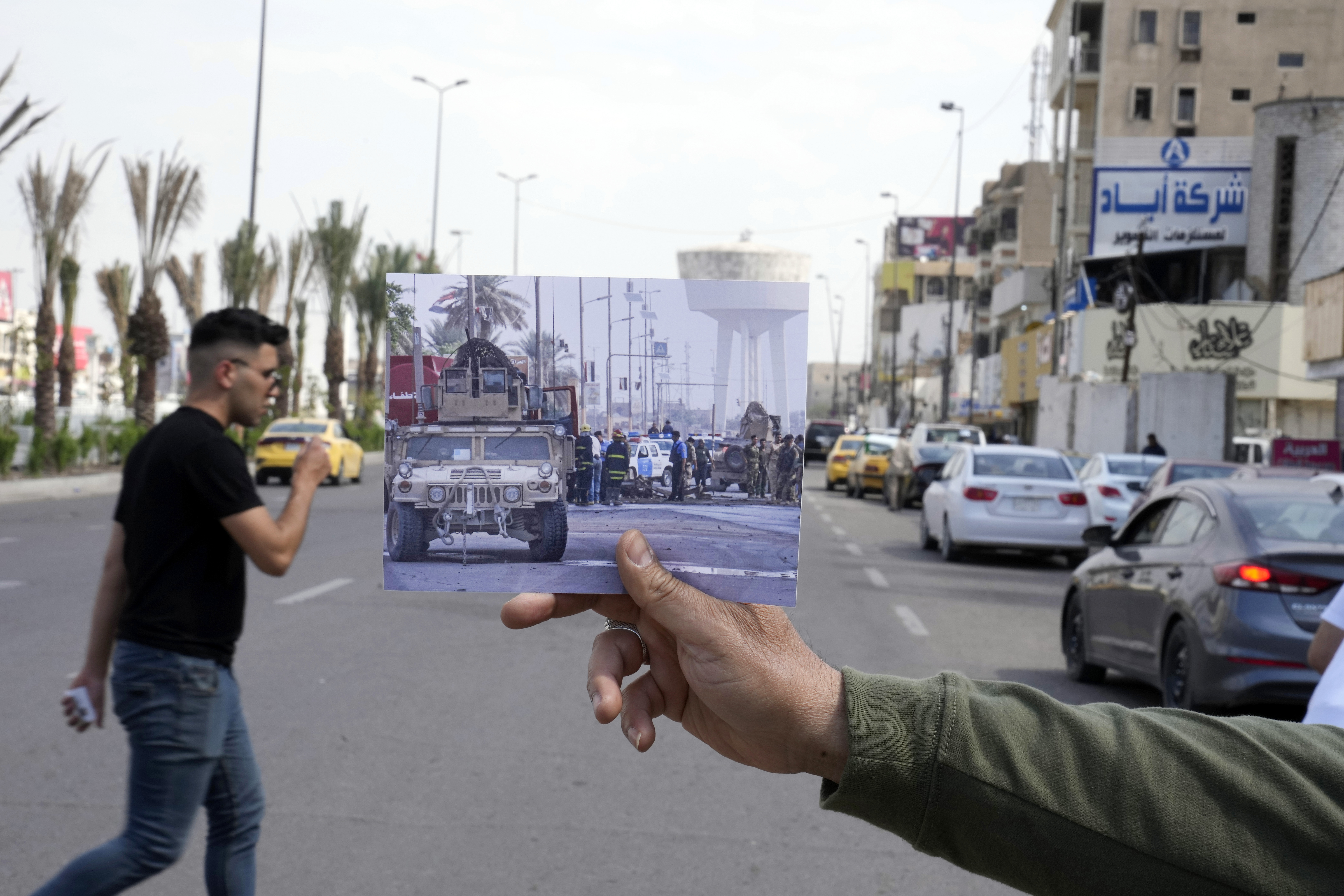 A photograph of a army vehicle securing the area where a suicide car bomber targeted a government convoy, in Bab al-Sharji area, central Baghdad, Thursday, Oct. 23, 2008, is inserted into the scene at the same location on Tuesday, March 21, 2023, 20 years after the U.S. led invasion on Iraq and subsequent war. 
