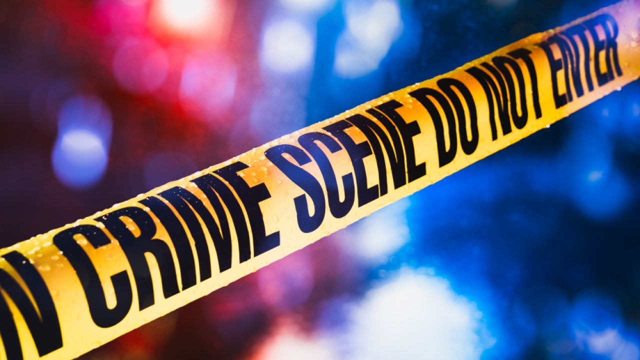 Crime scene tape with blurred police lights in the background