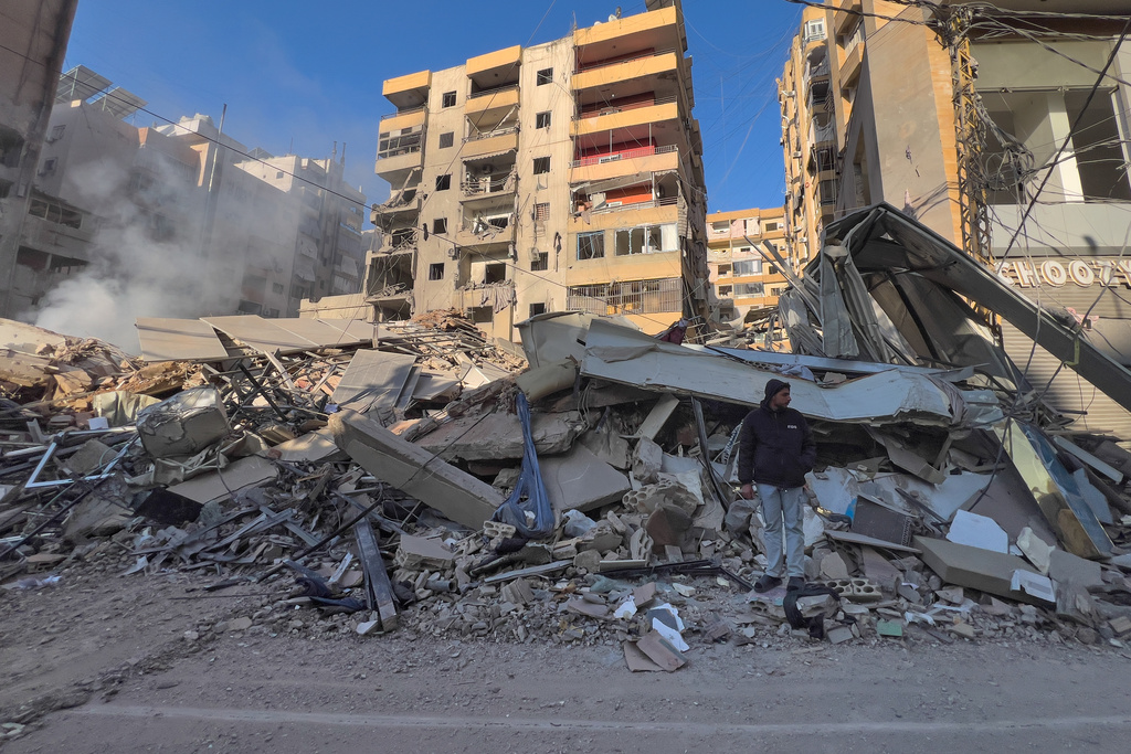 A man stands on the rubbles of a destroyed building that was hit by an Israeli airstrike in Dahiyeh, Beirut's southern suburbs, Lebanon, Tuesday, March 24, 2026. 
