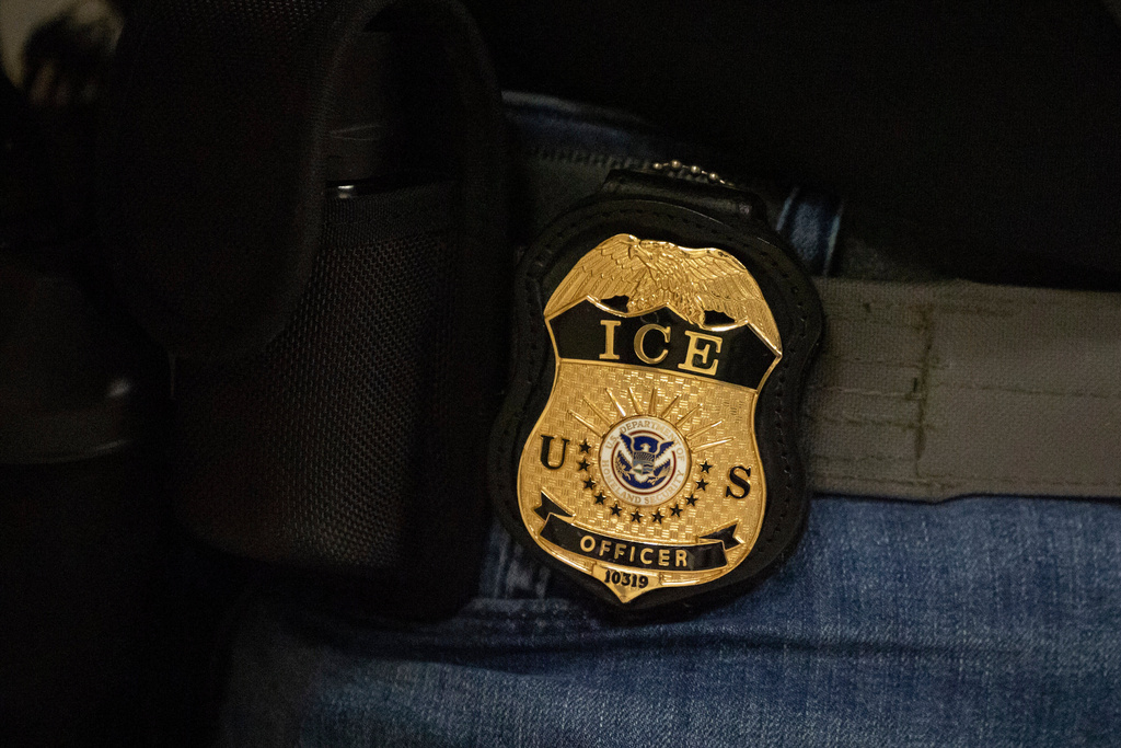 A federal agent wears an Immigration and Customs Enforcement badge.