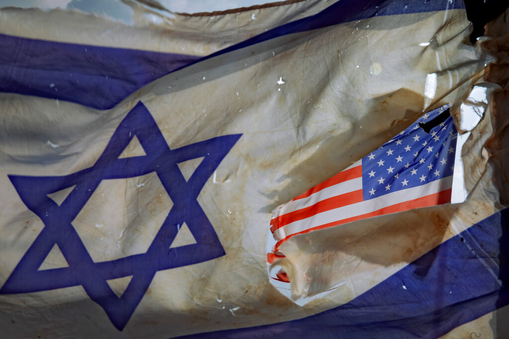 FILE- A U.S. flag is seen through a hole torn in an Israel national flag, as they wave in the wind at a horse ranch, near the southern Israeli town of Sderot, Friday, Nov. 20, 2020. 