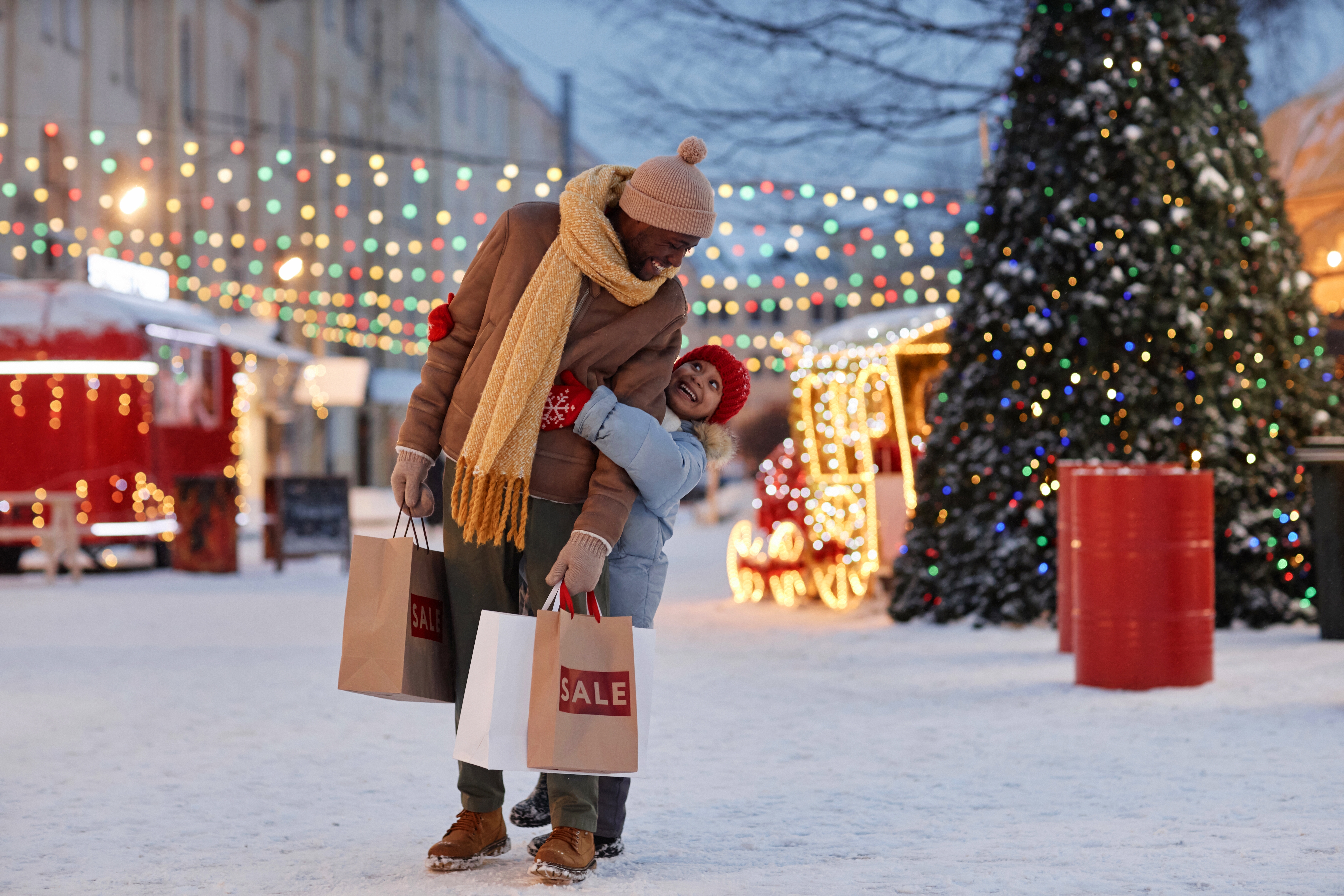 Full length portrait of happy girl with father having fun in winter outdoors enjoying Christmas shopping.