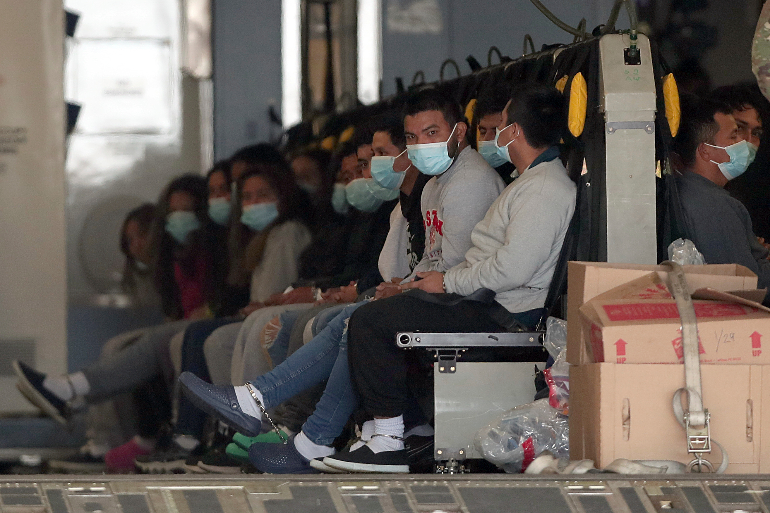 Migrants wearing face masks and shackles on their hands and feet sit on a military aircraft at Fort Bliss in El Paso, Texas, Jan. 30, 2025, awaiting their deportation to Guatemala. 