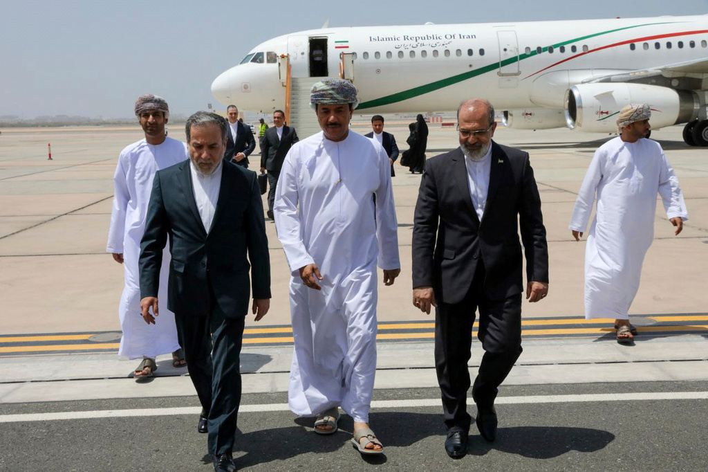 In this photo released by the Iranian Foreign Ministry, Iranian Foreign Minister Abbas Araghchi, left, is welcomed by an unidentified Omani official, center, upon his arrival at Muscat, Oman, for negotiations with U.S. Mideast envoy Steve Witkoff, as Iranian Ambassador to Oman Mousa Farhang walks at right, May 11, 2025. 