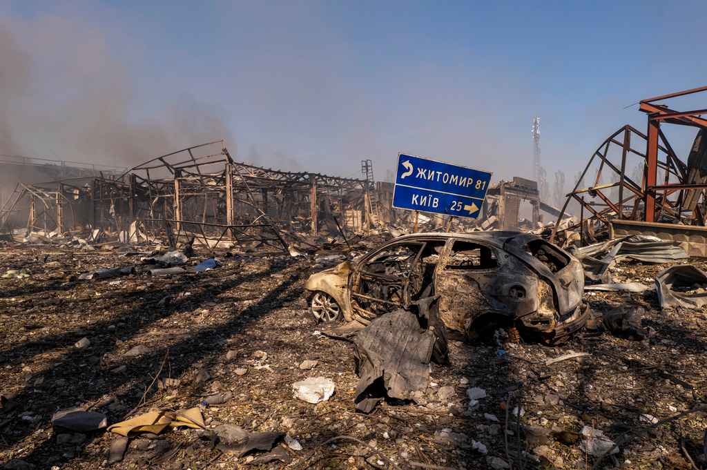 A view of a destroyed car amid damaged buildings, with a road sign showing the direction and distance to Kyiv and Zhytomyr after a Russian attack struck a warehouse, followed by an explosion, in the village of Myla, Kyiv region, Ukraine, Saturday, Aug. 29, 2026