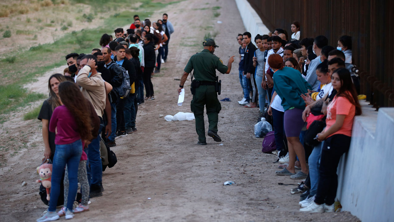 A group of migrants stand next to the border wall as a Border Patrol agent takes a head count in Eagle Pass, Texas, May 21, 2022. A surge in migration from Venezuela, Cuba and Nicaragua in September brought the number of illegal crossings to the highest level ever recorded in a fiscal year, according to U.S. Customs and Border Protection.