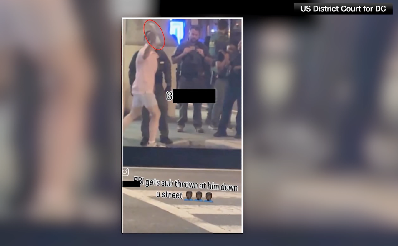 A screenshot of a video that shows a man throwing a sandwich at federal officers in D.C.
