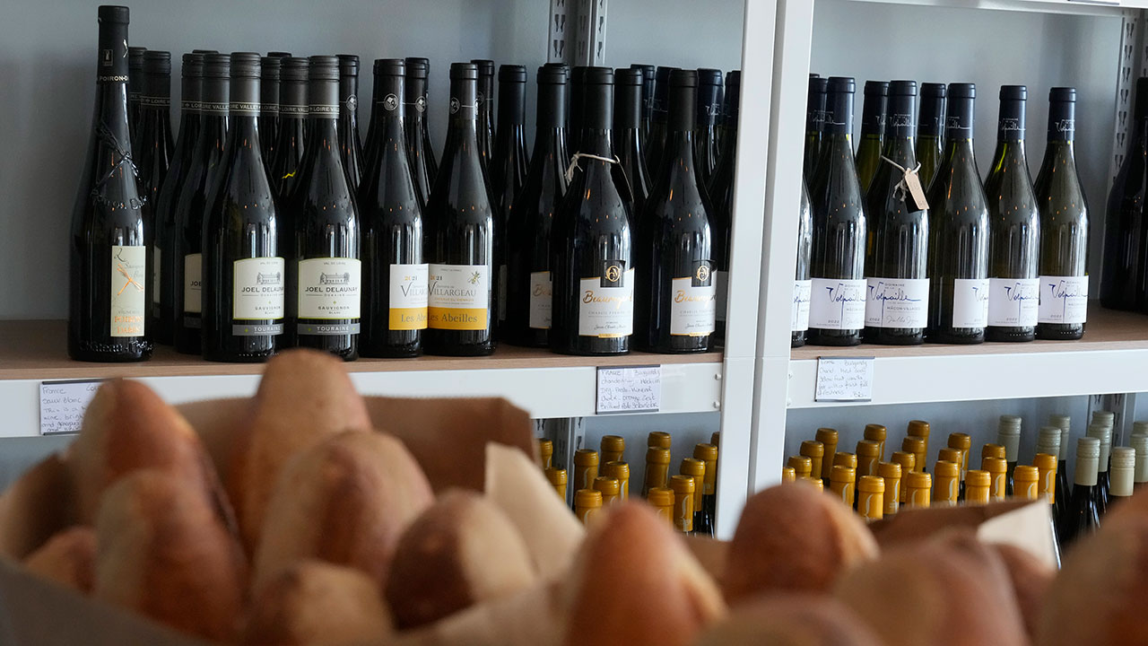Baguettes are shown in front of wines from France displayed at Galinette, a French bistro, in San Francisco, Friday, March 14, 2025.