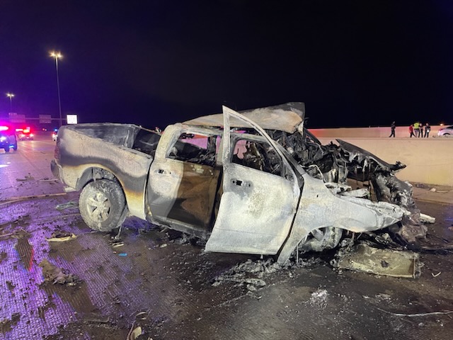 A photo of the scene released by the Utah Department of Public Safety. It's night, but the highway is fully lit. The Dodge Ram is left in a mix of white and grey as a result of the fire. The front of the vehicle where the engine once was is fully shattered and melted, with parts having been charred black.