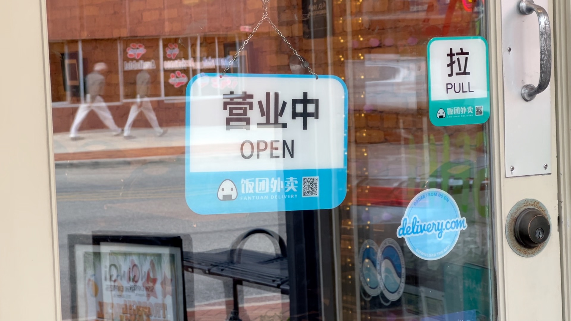 AnQi Sushi Express 'open' sign in Lansing as person walks by across the street