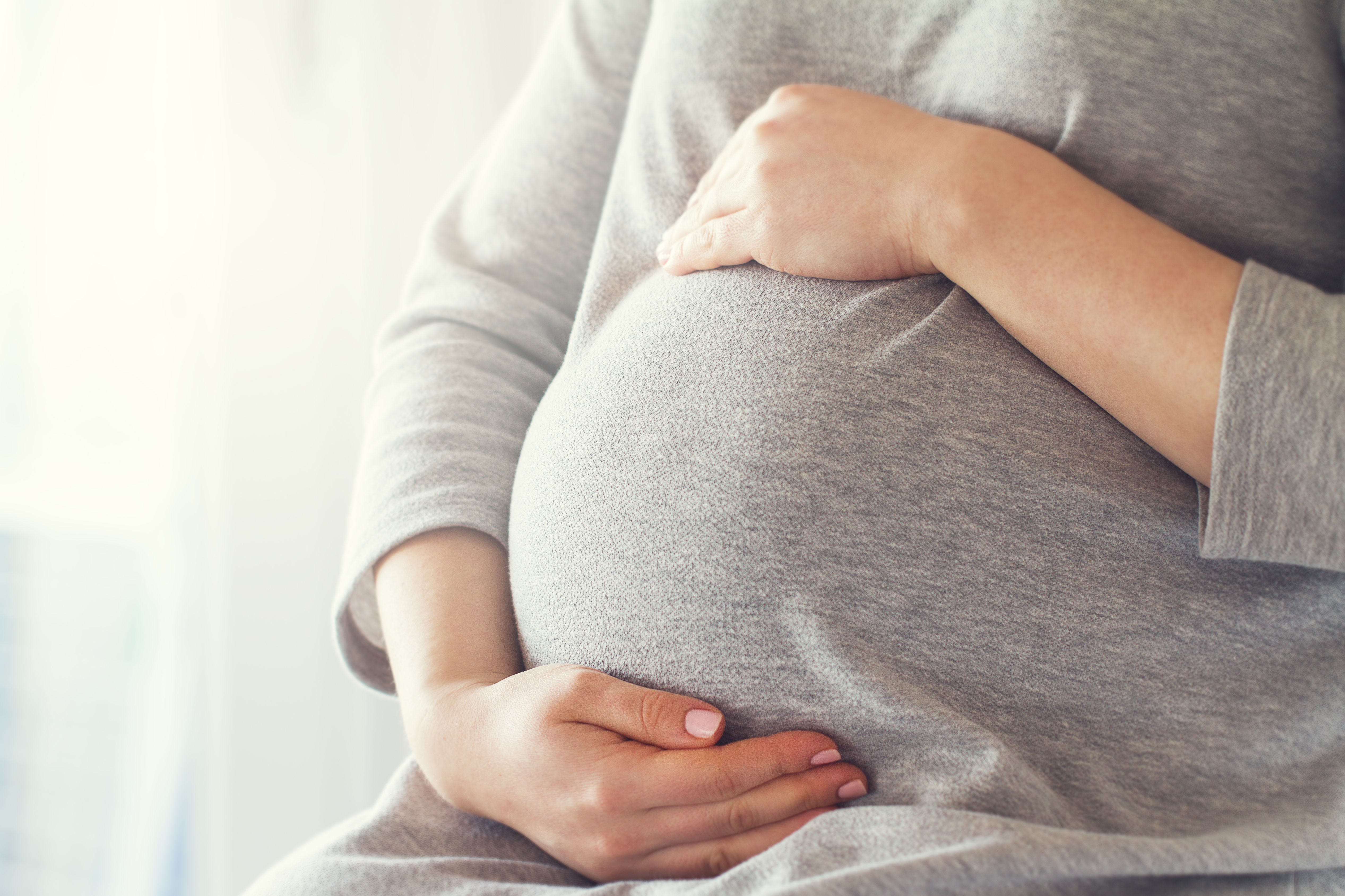 Young,Pregnant,Woman,Holds,Her,Hands,On,Her,Swollen,Belly.