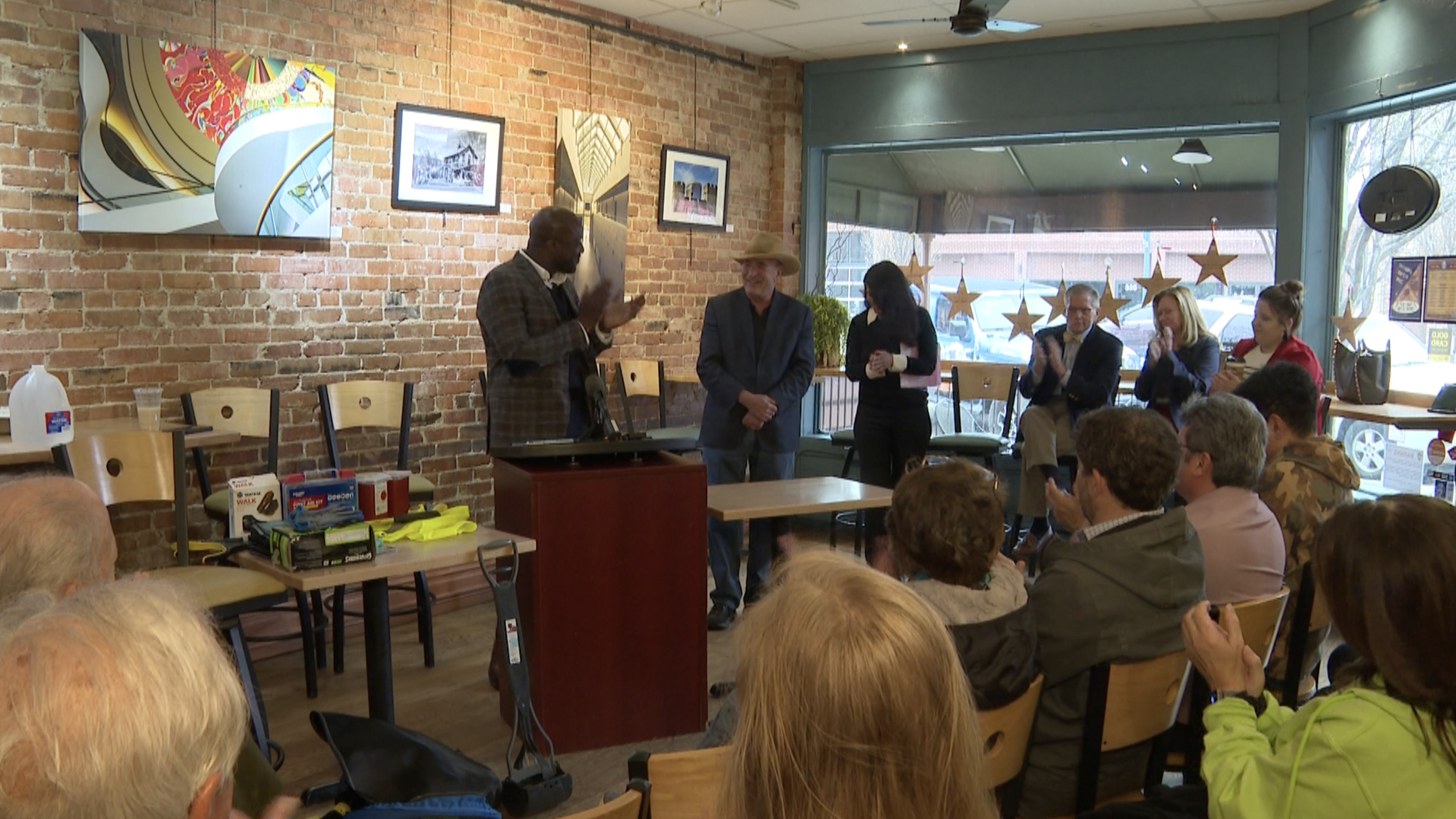 Photo of Mayor Yemi Mobolade applauding Richard Skorman at a coffee shop in Downtown Colorado Springs.