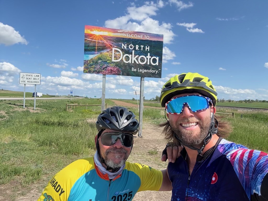 Todd and Charlie in front of the North Dakota sign 