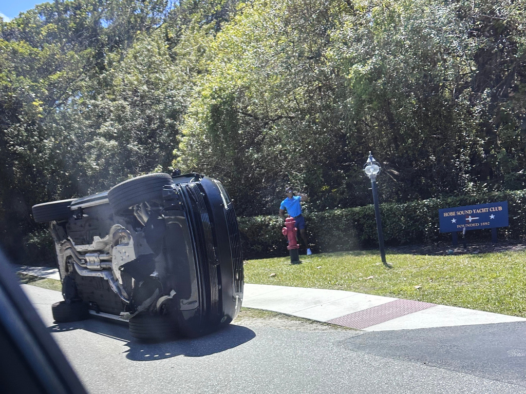 Golfer Tiger Woods stands by his overturned vehicle in Jupiter Island, Fla., Friday, March 27, 2026. 