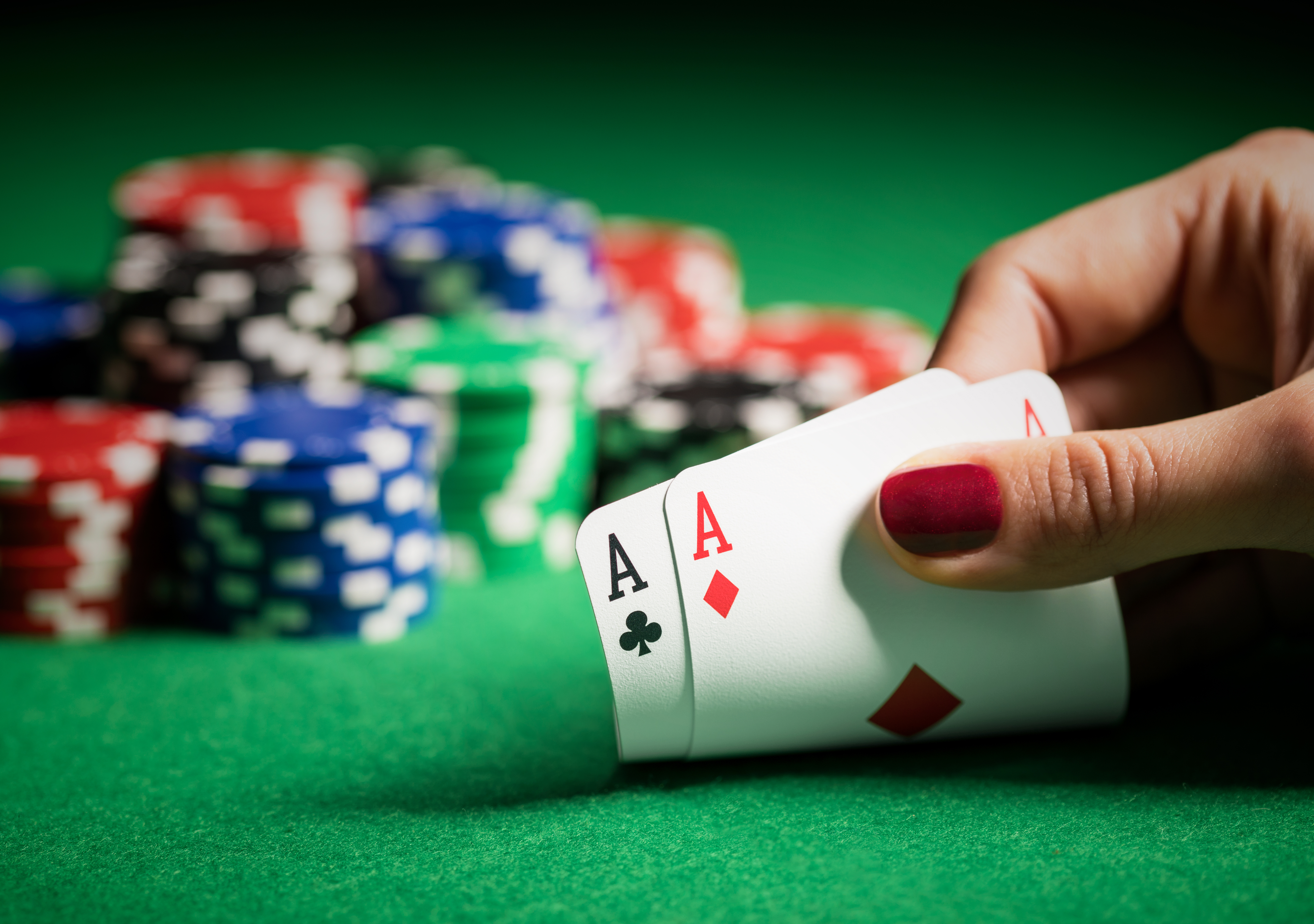 A woman holds up two aces at a poker table.