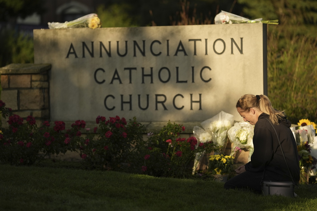 Ann Stovner kneels by a makeshift memorial at Annunciation Catholic Church after Wednesday's school shooting.