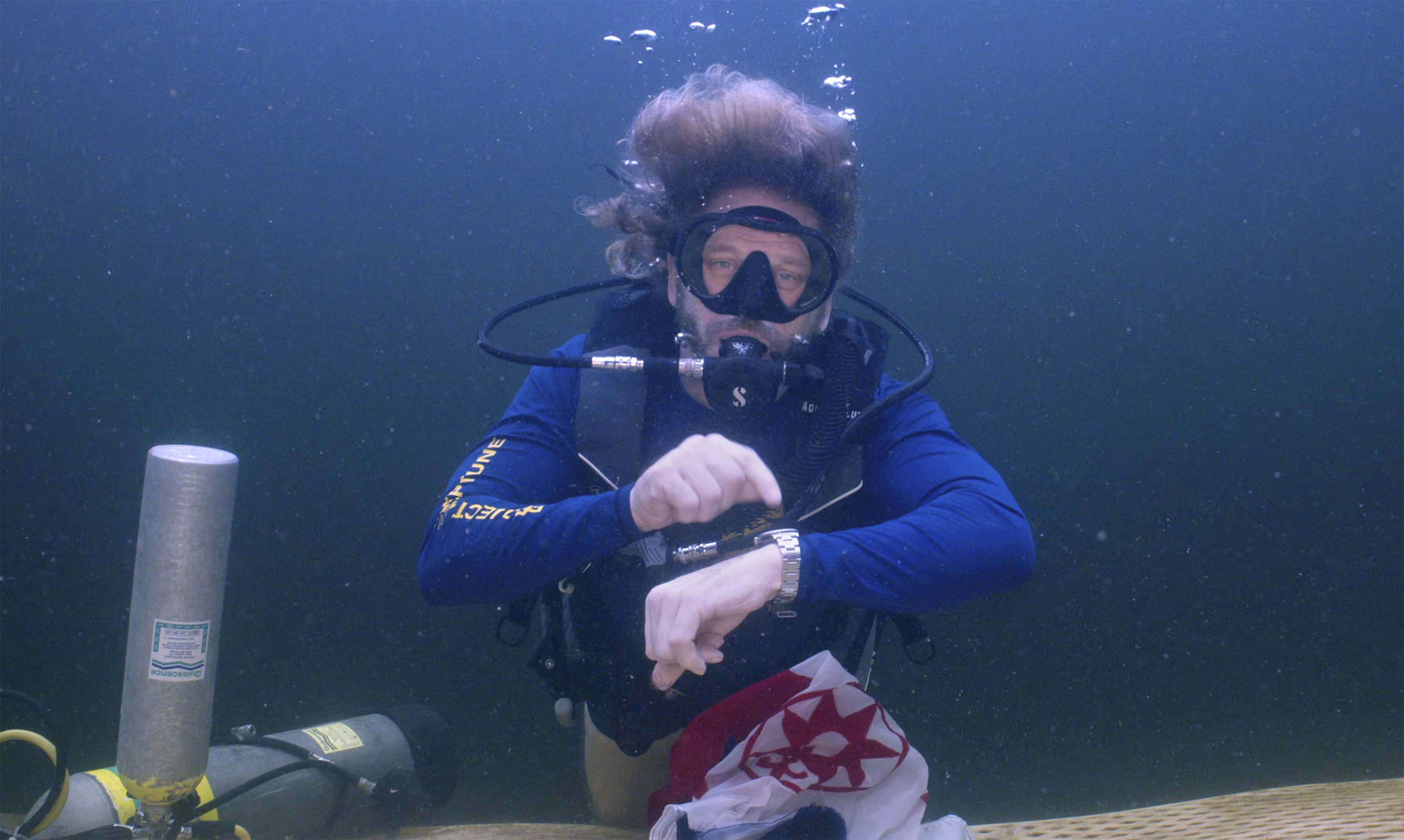 Diving explorer and medical researcher Dr. Joseph Dituri points to his watch Friday, indicating that it is time to surface after spending 100 days in the Jules' Undersea Lodge marine habitat at the bottom of a Key Largo, Fla., lagoon. 