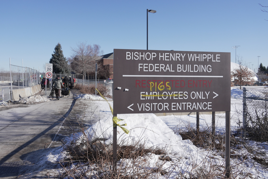 FILE - Protesters yell at cars coming and going near a defaced sign for Bishop Whipple Federal building in Minneapolis on Wednesday, Jan. 28, 2026. 