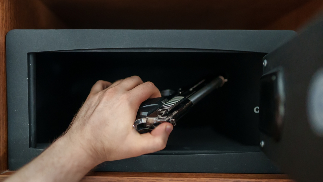 A person puts a gun in a safe.