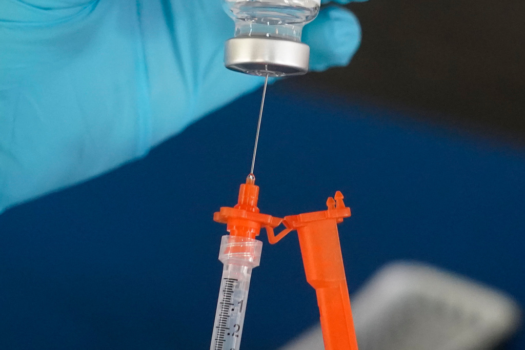 A nurse loads a syringe with a COVID-19 booster vaccine.