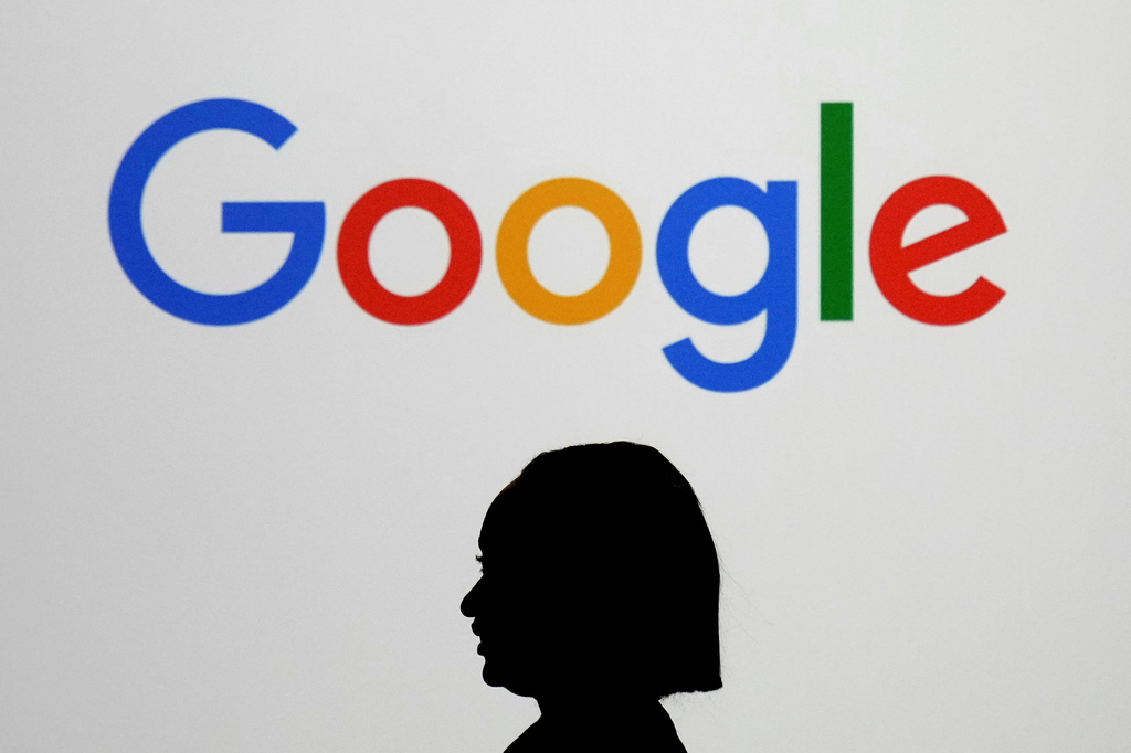 FILE - A woman walks by a giant screen displaying the Google logo at an event at the Paris Google Lab on the sidelines of the AI Action Summit in Paris, Feb. 9, 2025. 