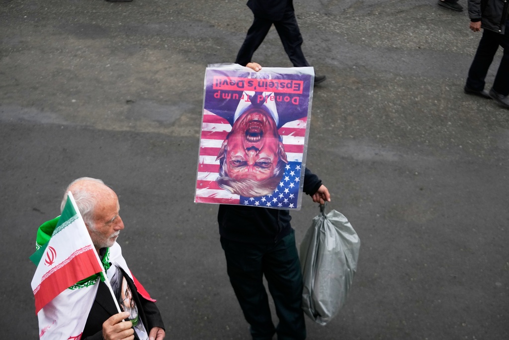 A man holds a picture of U.S. President Donald Trump upside down after Friday prayers at the Imam Khomeini Grand Mosque in Tehran, Iran, Friday, March 20, 2026. 