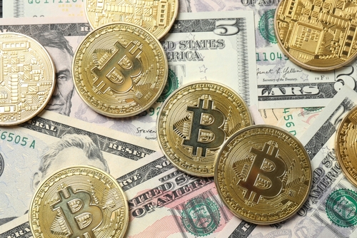 Stock image shows U.S. dollar bills and Bitcoin tokens.