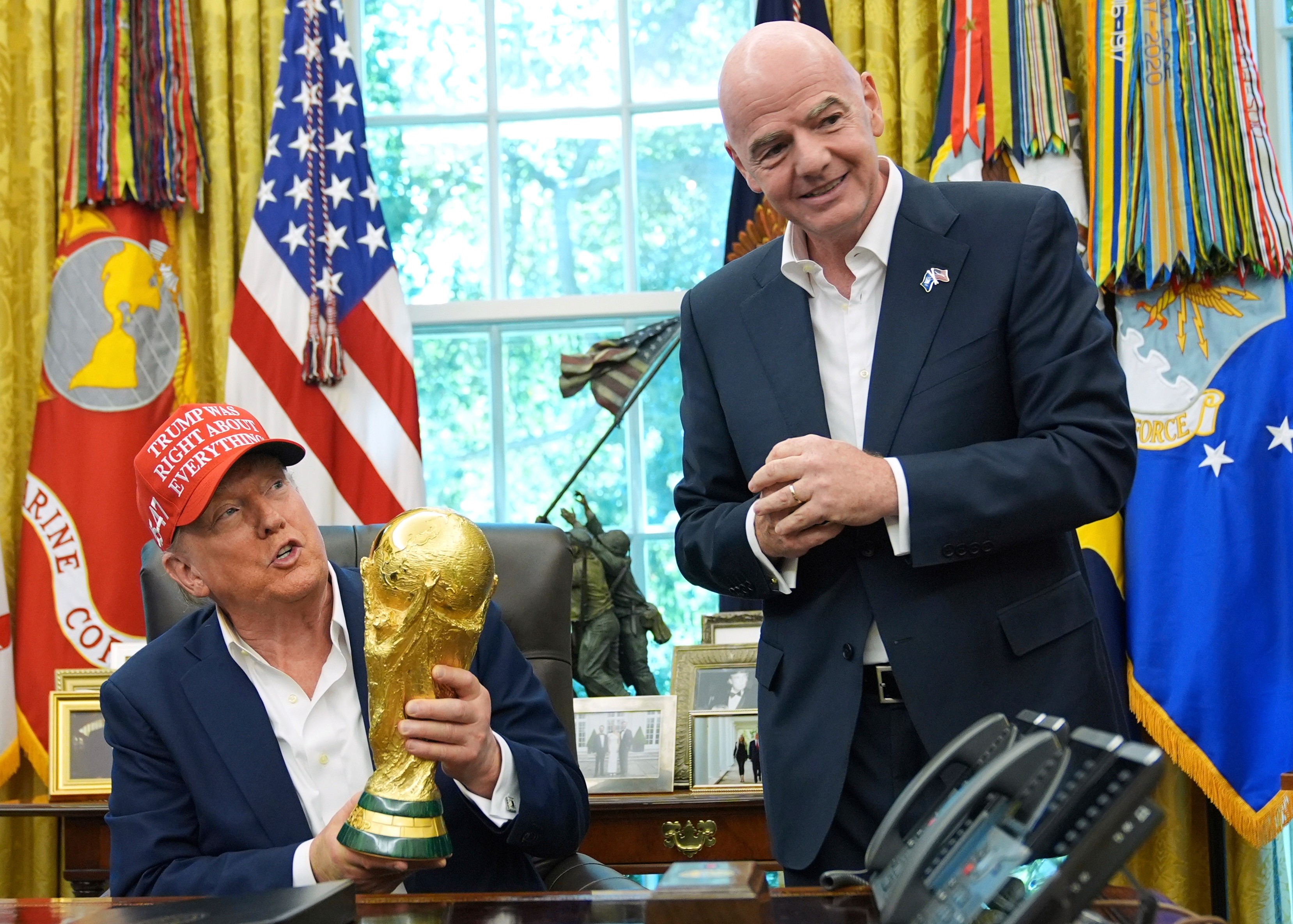 FILE - President Donald Trump holds the FIFA World Cup Winners Trophy as FIFA President Gianni Infantino looks on during an announcement in the Oval Office of the White House, Aug. 22, 2025, in Washington.