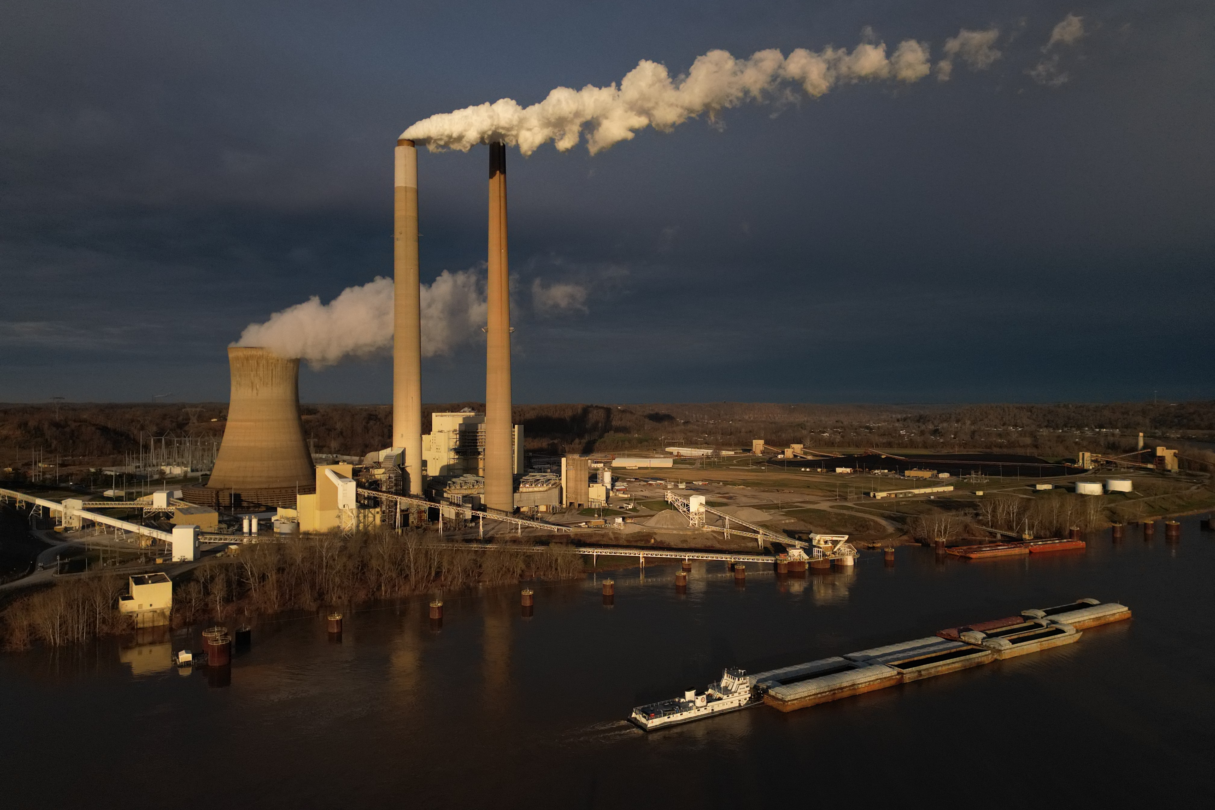 FILE - A barge on the Ohio River moves past the Mountaineer Power Plant, a coal-fired power plant near New Haven, W.Va., March 13, 2026.