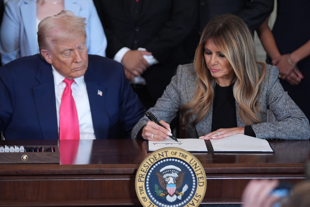 President Donald Trump watches as first lady Melania Trump adds her signature to an executive order during an event on foster care in the East Room of the at the White House, Thursday, Nov. 13, 2025, in Washington. 