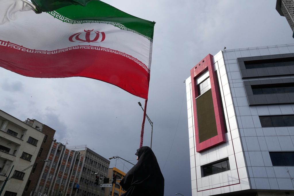 A woman holds an Iranian flag during a pro-government campaign in downtown Tehran, Iran, Sunday, May 17, 2026. 