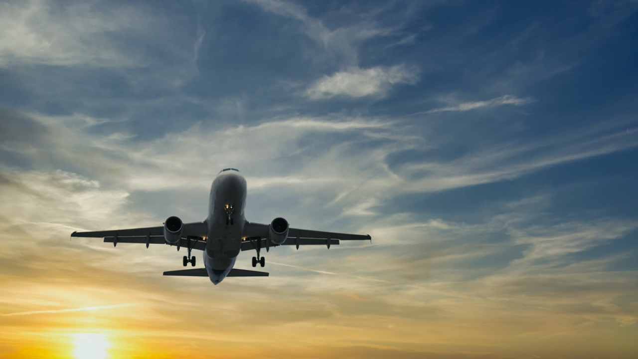 Airplane flying with sunset in the background.