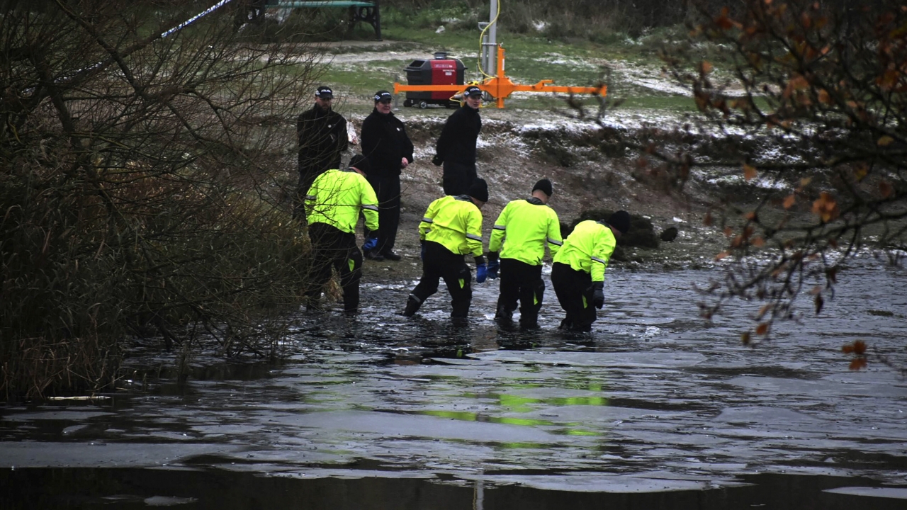 Police search teams investigate where four children fell through an icy lake.