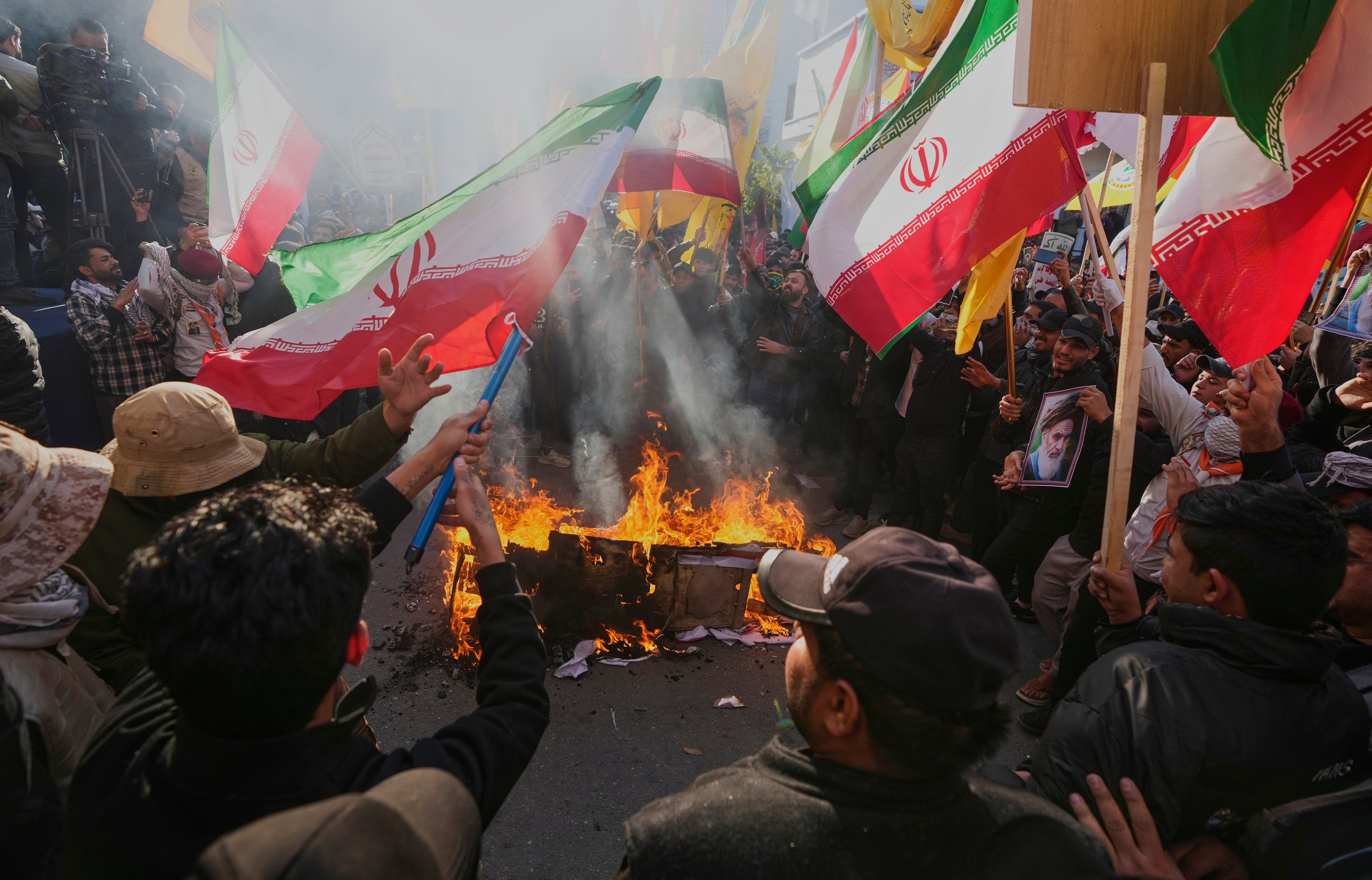 Protesters burn depictions of the Israeli and U.S. flags, during a rally to show solidarity with Iran and oppose the U.S. threats of a military strike, in Baghdad, Iraq, Friday, Jan. 16, 2026.
