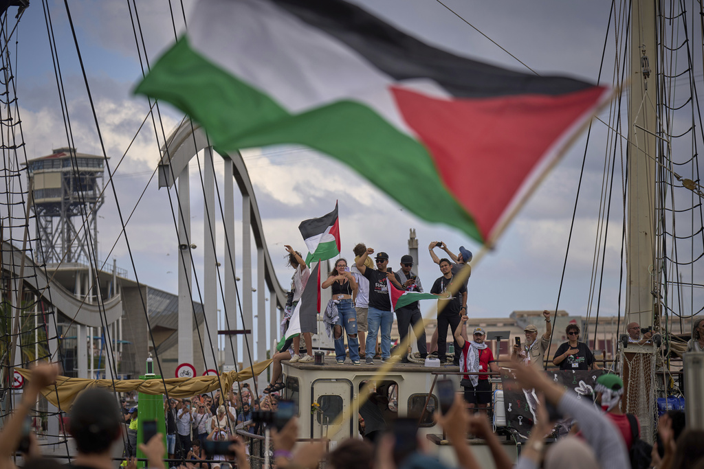 Activists wave on a boat taking part in a civilian flotilla bound for Gaza.