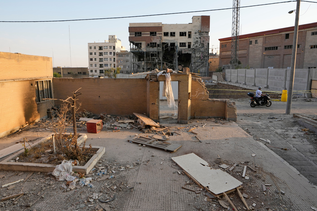 A motorbike drives past residential buildings damaged in a U.S.-Israeli strike on March 8 and remained in ruins in Tehran, Iran, Thursday, Aug. 27, 2026. 