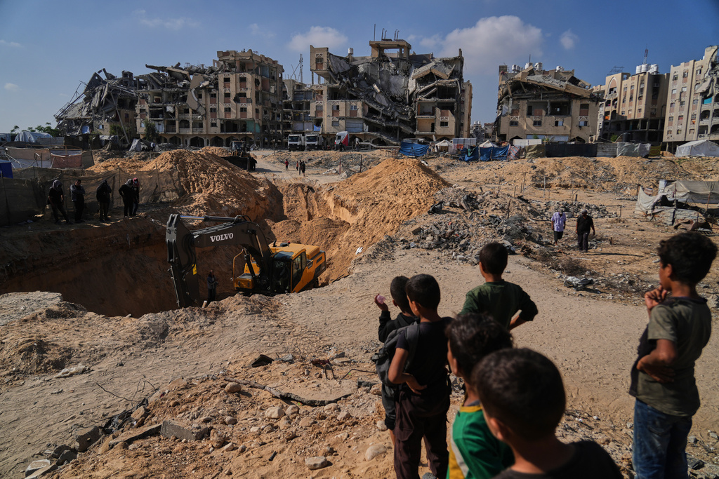 Palestinians watch as Egyptian machinery and workers search for the bodies of hostages in Hamad City, Khan Younis, in the southern Gaza Strip, Tuesday, Oct. 28, 2025.