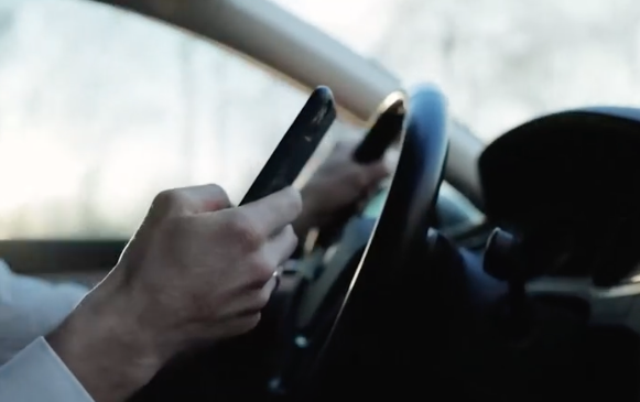 Distracted driver useing a cell phone while behind the wheel.png