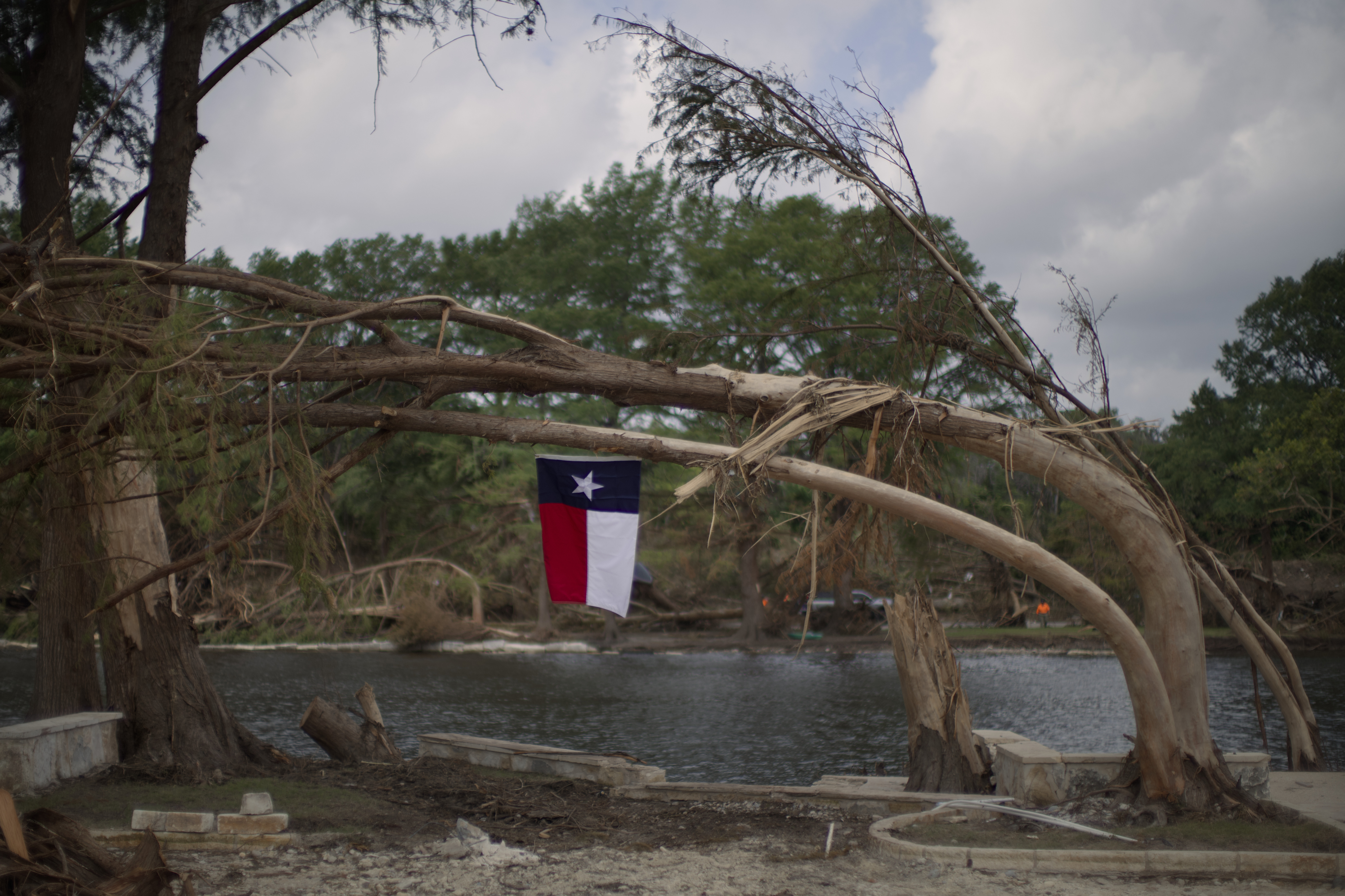 A Texas flag hangs from a flood-damaged tree on the bank of the Guadalupe River, Saturday, July 12, 2025, in Kerrville, Texas. 