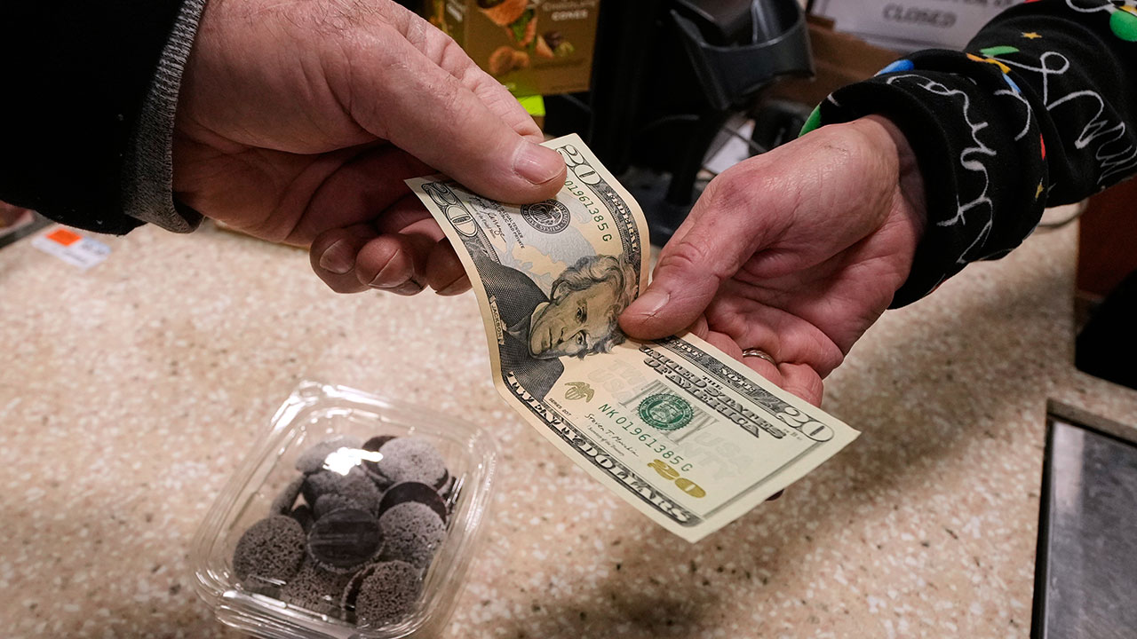 A shopper pays with cash for a container of candy at a store, Thursday, Dec. 11, 2025, in Salem, N.H.