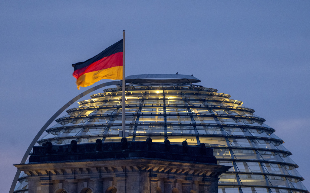 A German national flag waves on top of the Reichstag building in Berlin, Germany.
