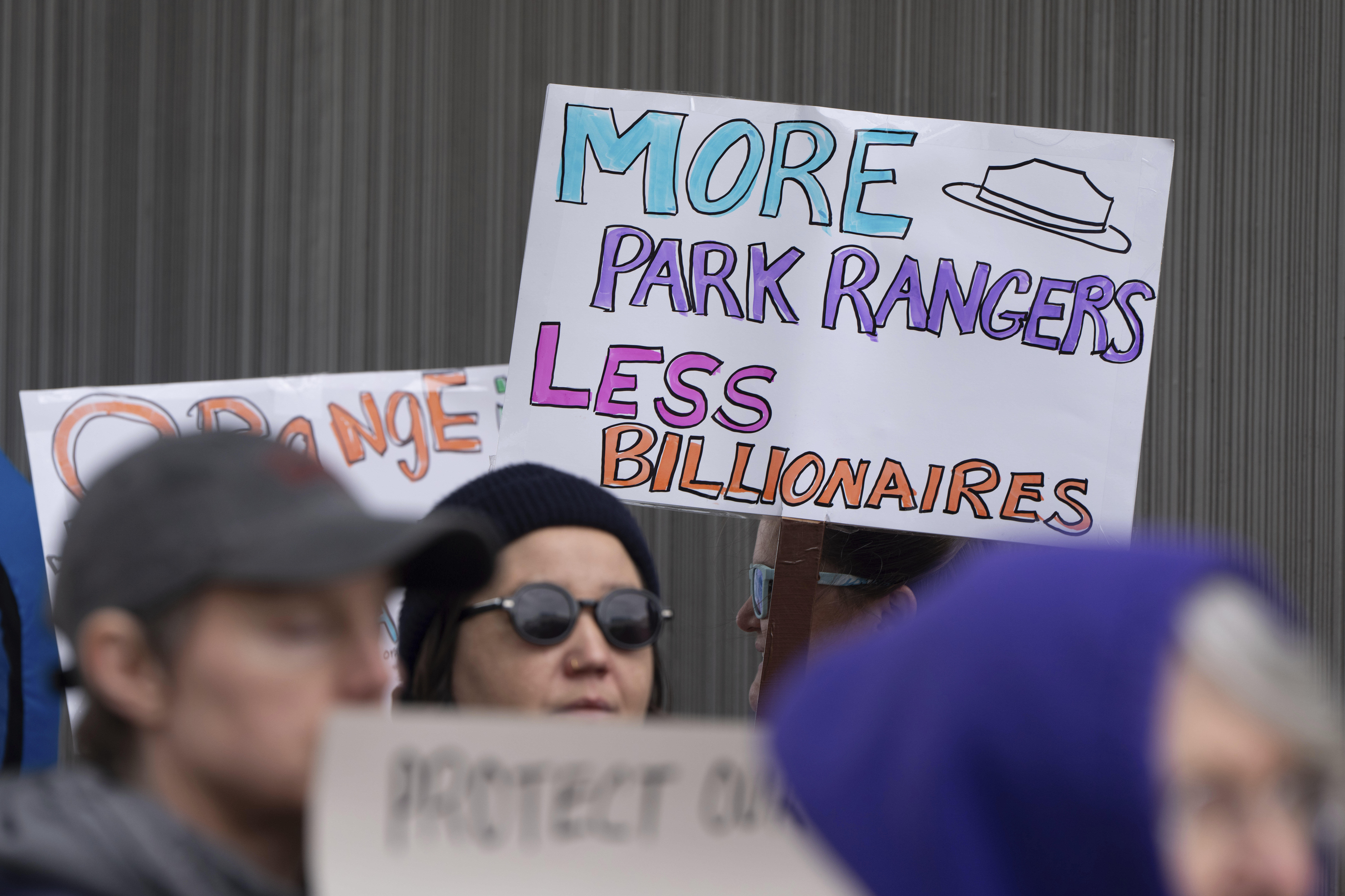 People hold signs during a protest outside the annual Alaska Sustainable Energy Conference, June 3, 2025, in Anchorage, Alaska.