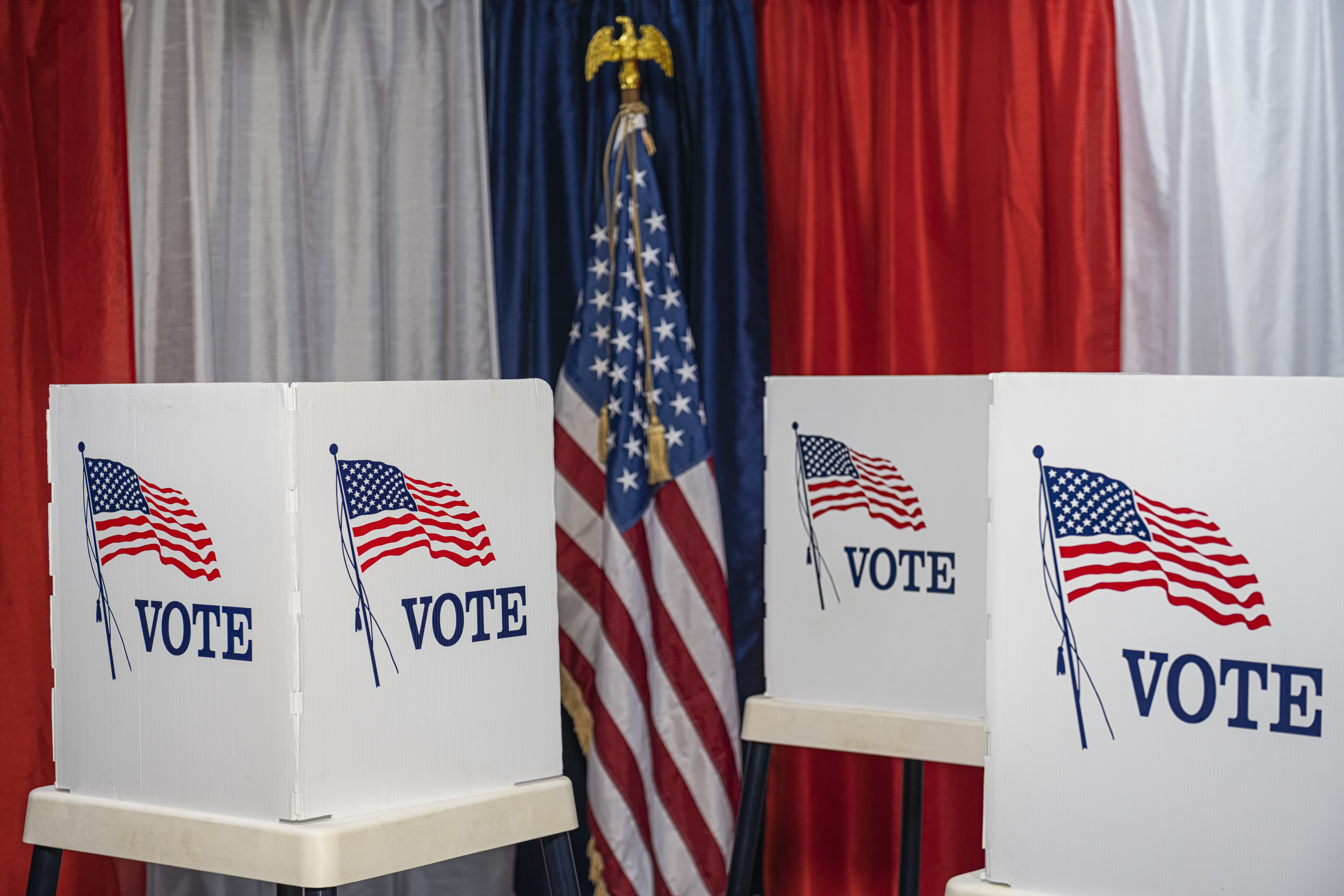 Three empty voting booths with bunting and American flag