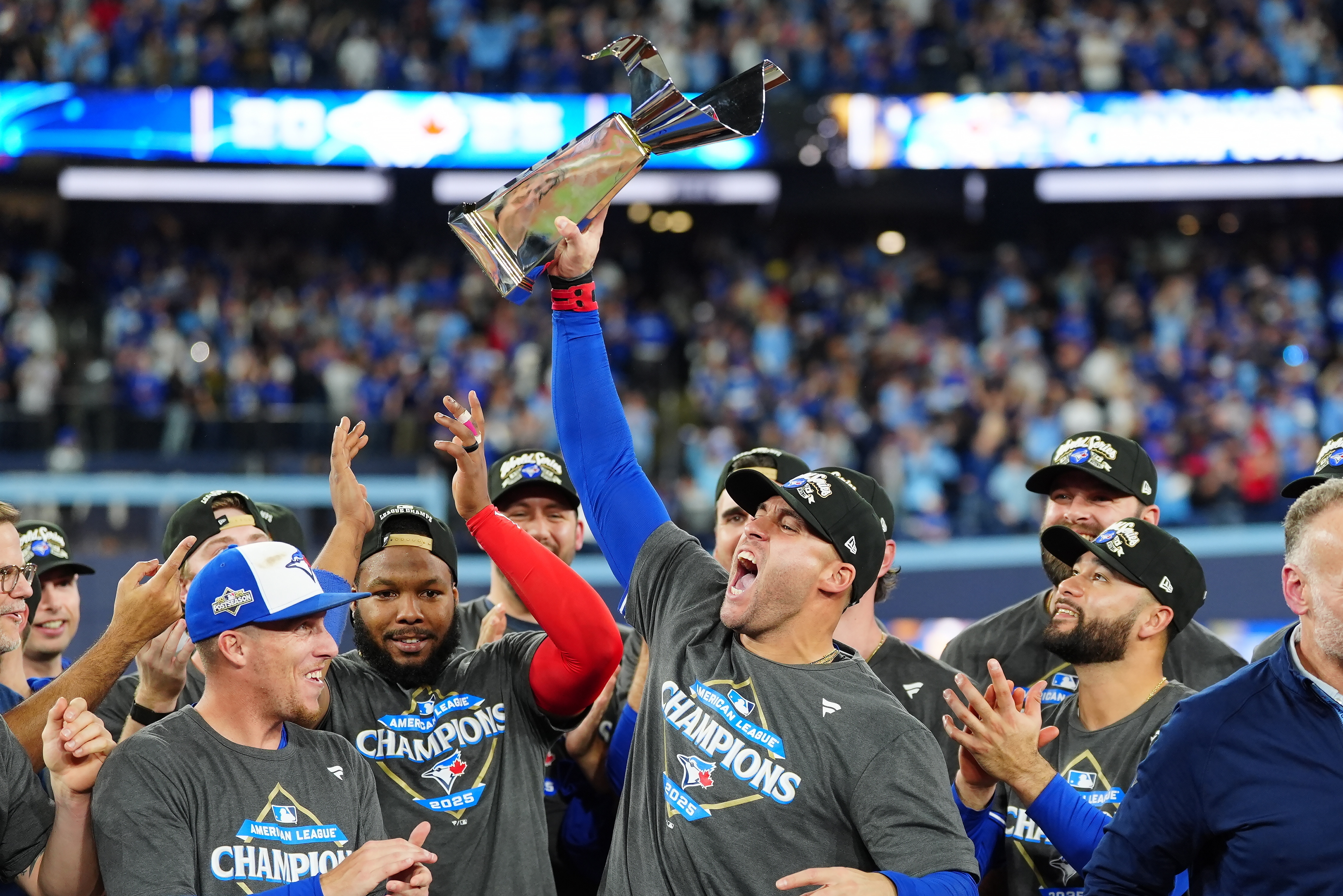 Toronto Blue Jays' George Springer holds the American League Championship Series trophy as the team celebrates after defeating the Seattle Mariners in Game 7 of the series in Toronto, Monday, Oct. 20, 2025. 