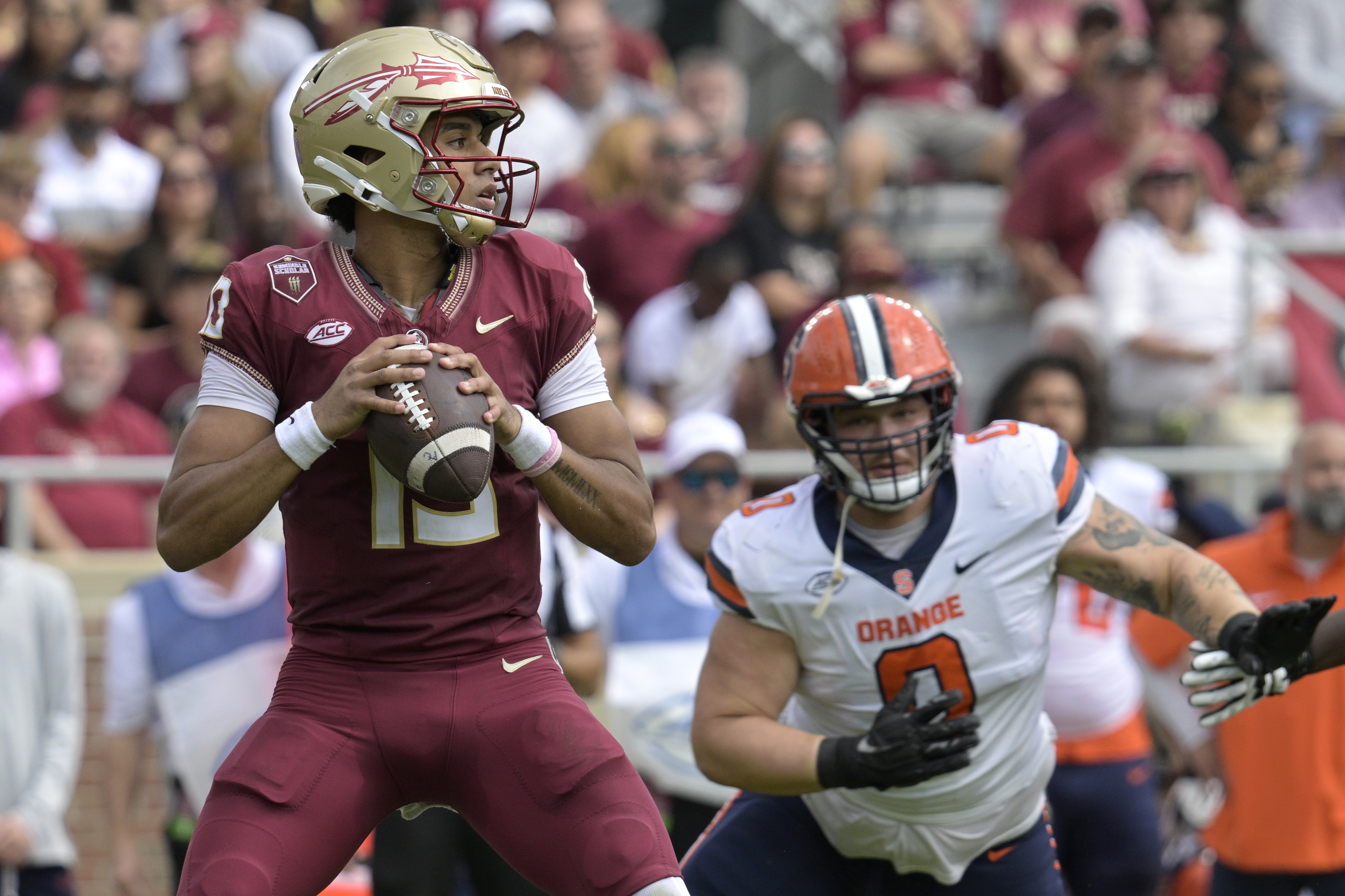 Florida State Seminoles QB Jordan Travis (13) looks for receiver as Syracuse defensive lineman Kevon Darton pursues him in first half, Oct. 14, 2023