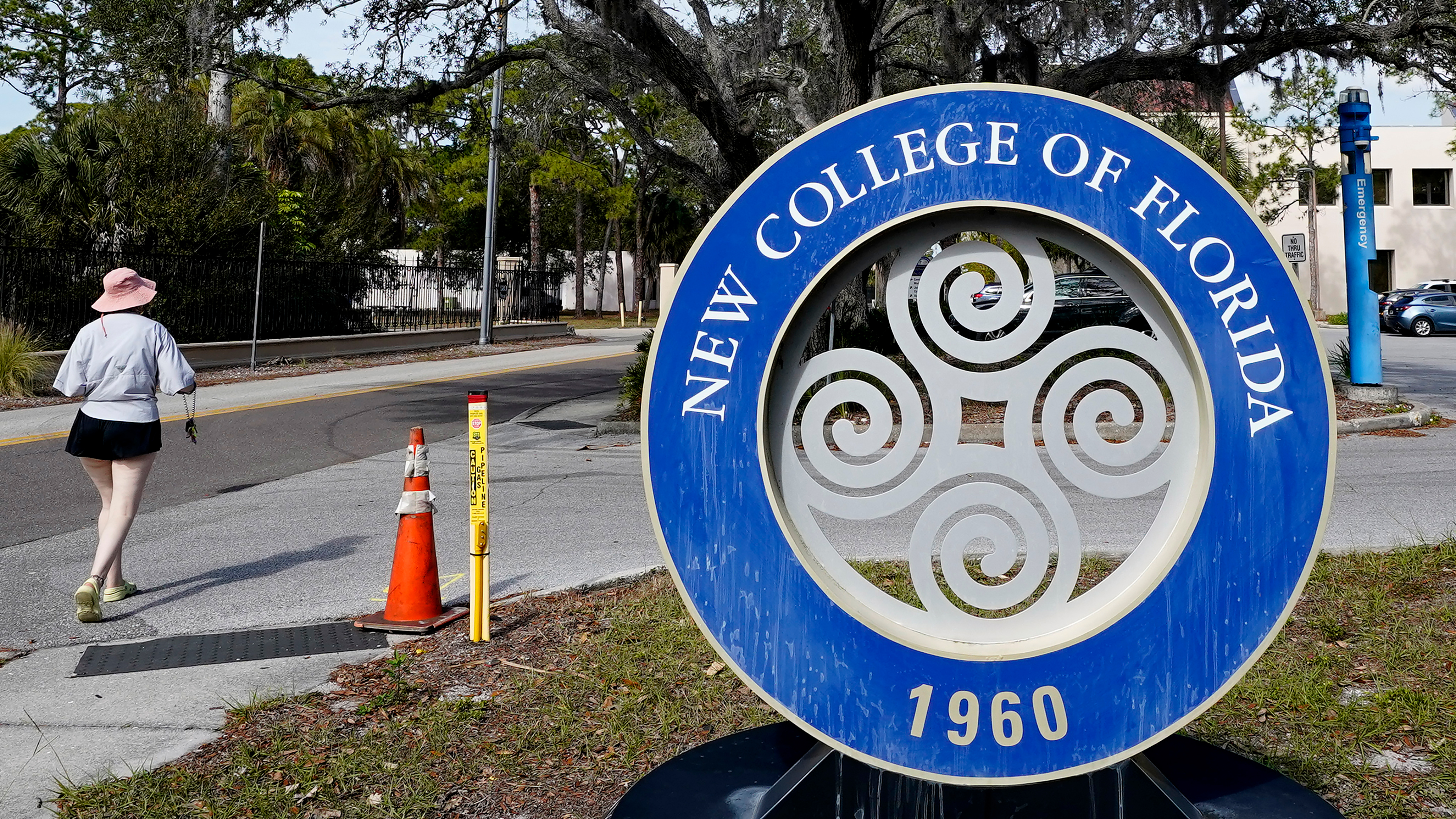 FILE - A student makes her way past the sign at New College of Florida, Jan. 20, 2023, in Sarasota, Fla. The New College of Florida trustees now dominated by conservatives appointed by Gov. Ron DeSantis voted Wednesday, April 26, 2023, to deny tenure to five professors, overriding concerns by faculty and students that the decision poses a threat to academic freedom. 