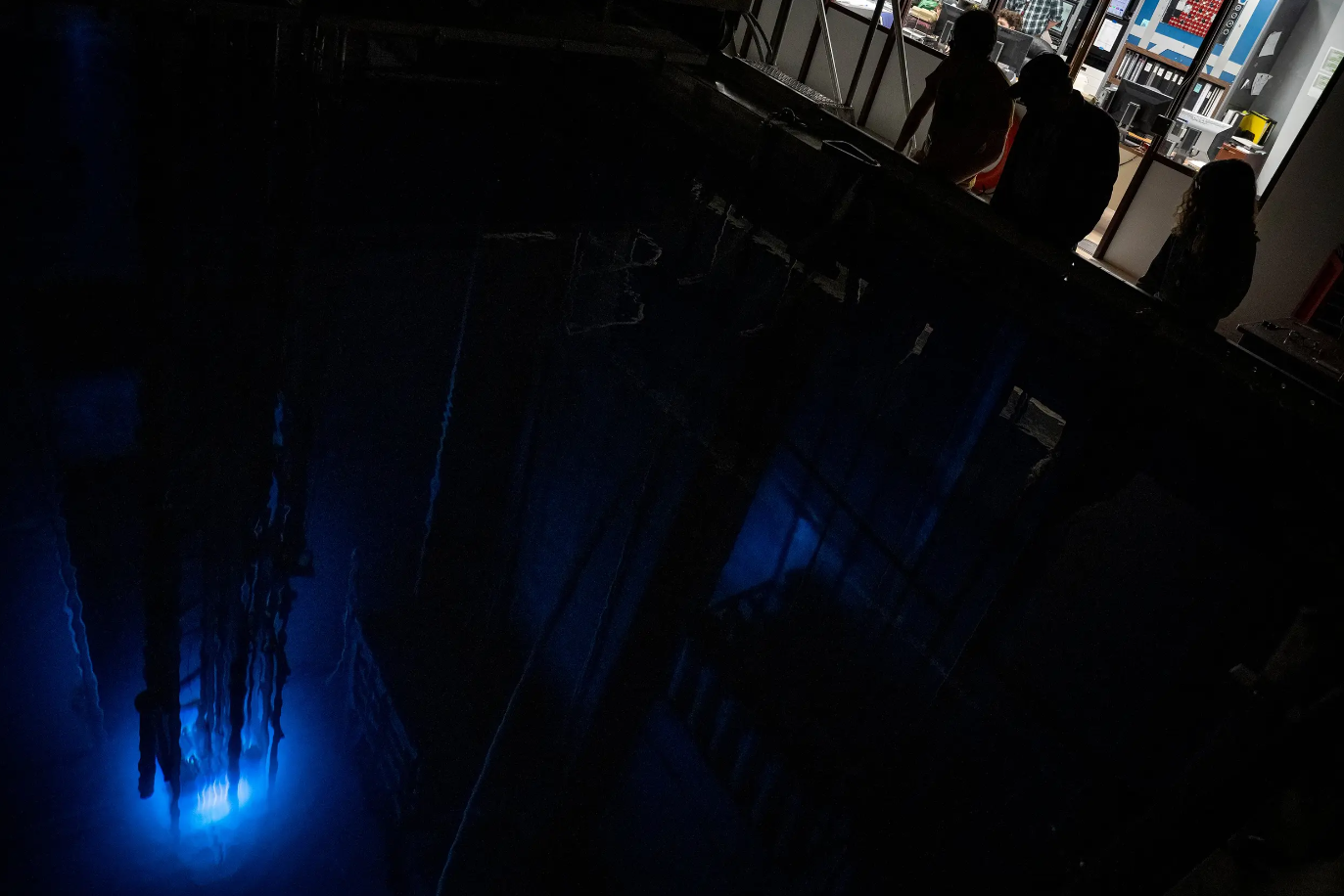 Operators peer into the reactor pool where Texas A&M University’s Training, Research, Isotopes, General Atomics (TRIGA) nuclear research reactor emits a blue glow on March 11, 2024 in College Station.