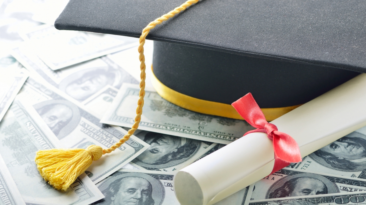 Graduation cap on top of a pile of money.