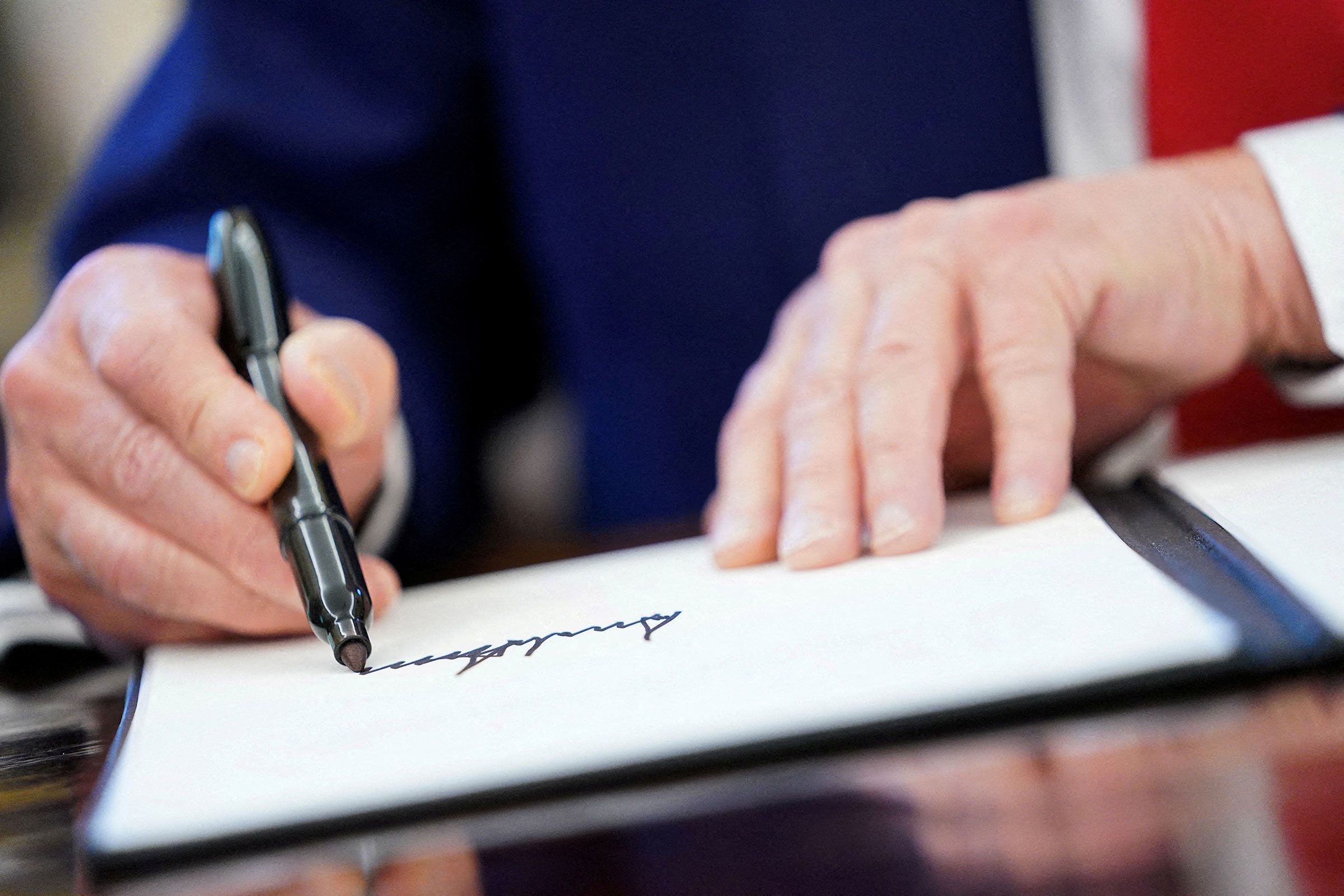 President Donald Trump writes his signature, as he signs executive orders and proclamations in the Oval Office at the White House in Washington, D.C., in April 2025.